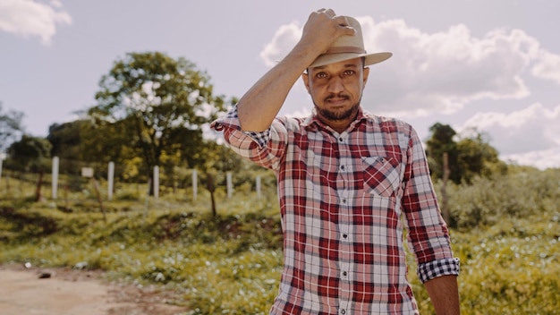 Porträt eines jungen Mannes im Freizeithemd, der auf dem Bauernhof den Hut aufsetzt