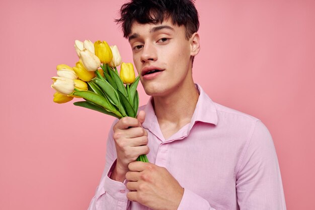 Porträt eines jungen Mannes in einem rosa Hemd mit einem Blumenstrauß, der mit seinen Händen gestikuliert Lifestyle unverändert