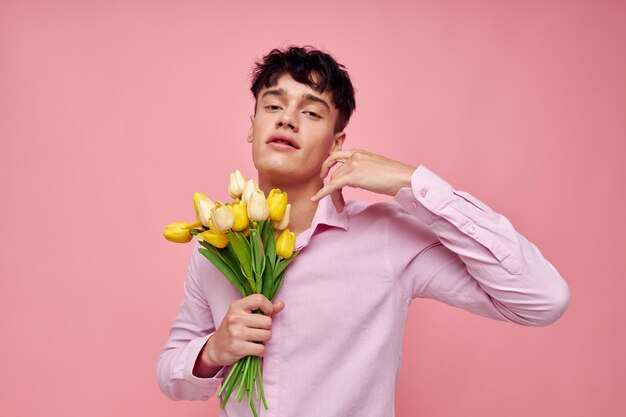 Porträt eines jungen Mannes in einem rosa Hemd mit einem Blumenstrauß, der mit seinen Händen gestikuliert Lifestyle unverändert