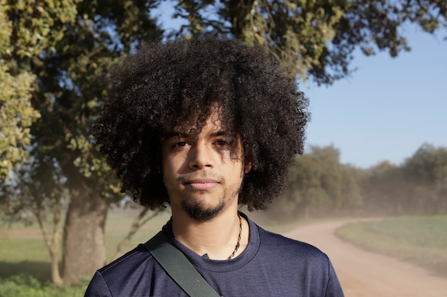 Porträt eines jungen Mannes mit Afro, der in einem Freiluftfeld schaut