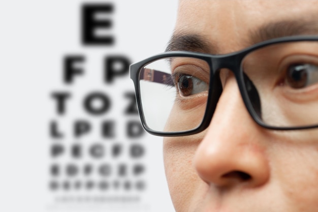 Foto porträt eines jungen mannes mit brille mit sehtestkarte isoliert auf weißem hintergrund