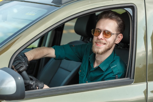 Porträt eines jungen Mannes mit dunkler Brille, der ein Auto fährt