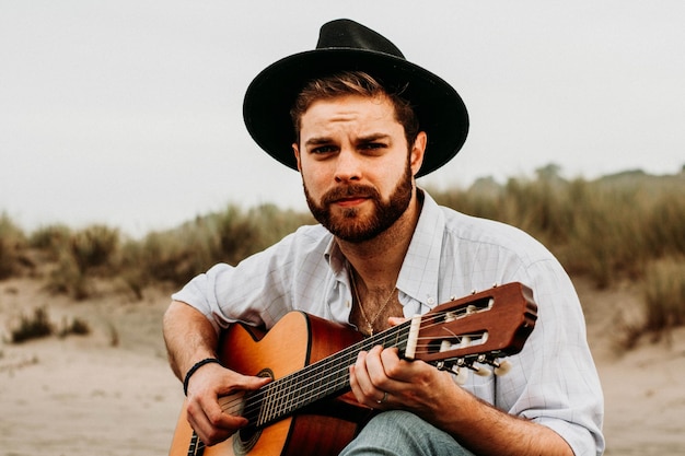 Porträt eines jungen Mannes mit Gitarre am Strand