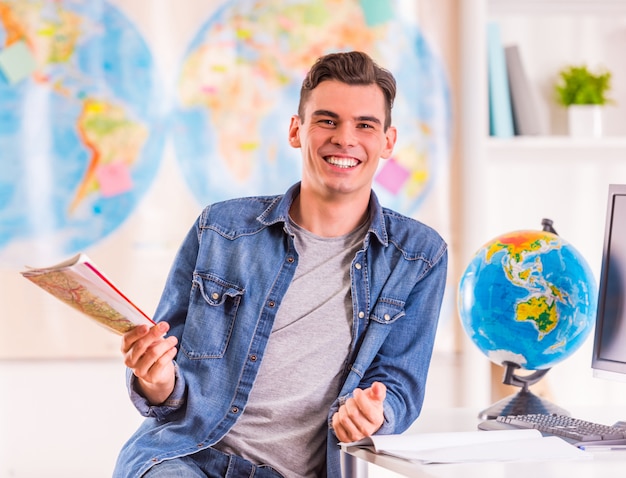 Porträt eines jungen Mannes wählt für die Reise unter Verwendung einer Karte aus.