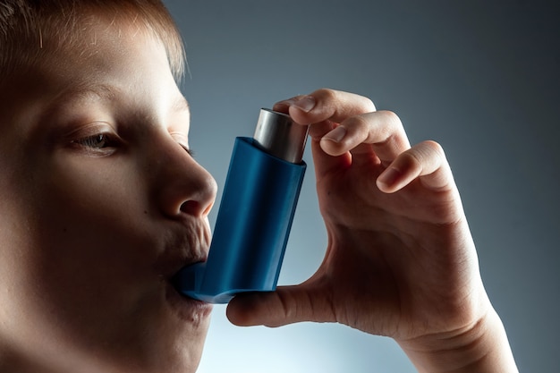 Porträt eines Jungen mit einem Asthmainhalator zur Behandlung von entzündlichen Erkrankungen, Atemnot. Das Konzept der Behandlung von Husten, Allergien, Atemwegserkrankungen.