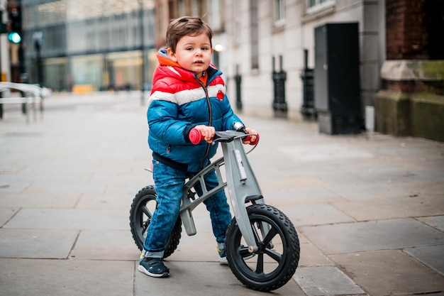 Foto porträt eines jungen mit fahrrad, der auf der straße steht