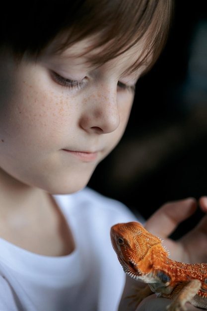 Porträt eines Jungen mit rotem Bart, einem Agama-Iguana, ein kleines Kind, das mit Reptilien selektiv fokussiert spielt