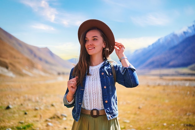 Porträt eines jungen netten, attraktiven lächelnden Mädchenreisenden des Hippies, der in einem Gebirgstal reist