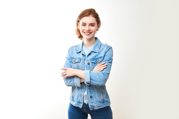 Porträt eines jungen rothaarigen Mädchens auf einem weißen lokalisierten Hintergrund in den Jeans. Schaut in die Kamera