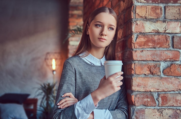 Porträt eines jungen, schlanken, sinnlichen Mädchens in einem grauen Kleid, das ag lehnt