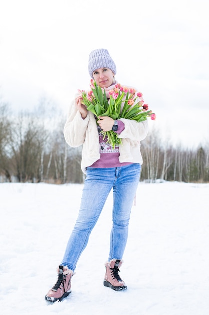 Porträt eines jungen schönen Mädchens auf der Straße im Winter mit Tulpen