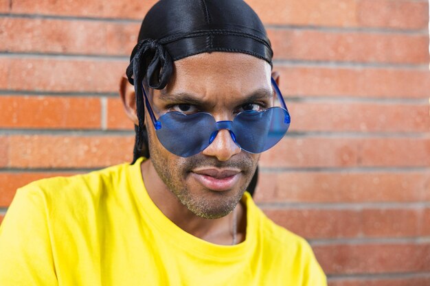 Porträt eines jungen schwarzen Mannes mit farbiger Brille, der in die Kamera schaut