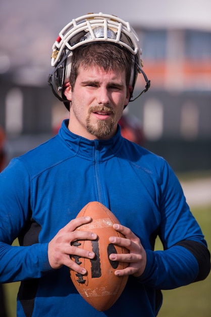 Porträt eines jungen, selbstbewussten American-Football-Spielers, der während des Trainings auf einem Feld steht