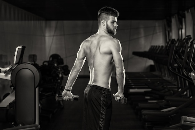 Porträt eines jungen sportlichen Mannes im modernen Fitnessstudio mit Trainingsgeräten