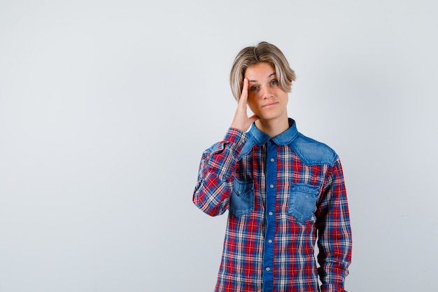 Porträt eines jungen Teenagers mit Hand an der Seite des Gesichts in kariertem Hemd und intelligenter Vorderansicht