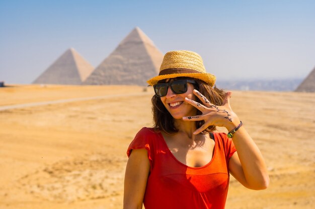 Porträt eines jungen Touristen in roter Kleidung, der die Pyramiden von Gizeh genießt, das älteste Grabdenkmal der Welt. In der Stadt Kairo, Ägypten