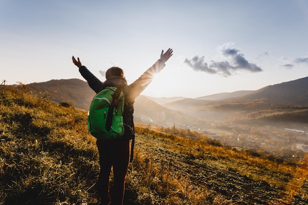 Porträt eines jungen Touristen mit grünem Rucksack, der die natürliche Schönheit bewundert Spätherbstberge an sonnigen Tagen Der beste Weg, um in einer sich schnell verändernden Welt langsamer zu werden Genießen Sie das Moment-Konzept