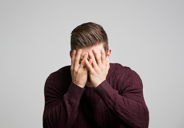 Porträt eines jungen weißen Mannes mit Händen, die sein Gesicht bedecken