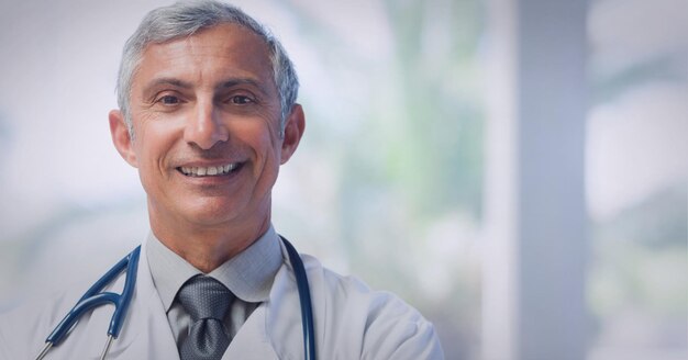 Porträt eines kaukasischen leitenden männlichen Arztes, der einen Laborkittel trägt und im Krankenhaus lächelt