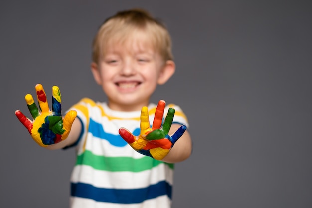 Porträt eines Kindes mit bemalten Händen, glücklicher Junge 5-6 Jahre alt