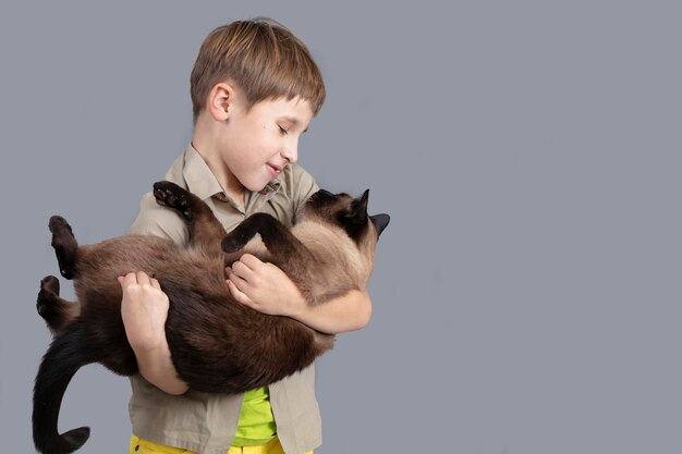 Porträt eines Kindes mit einer Katze Ein Junge mit einer siamesischen Katze