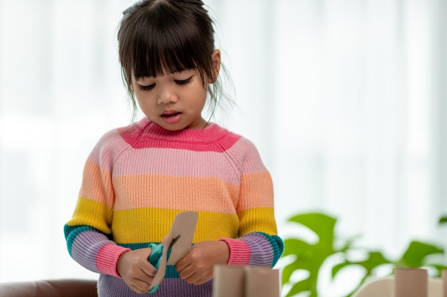 Porträt eines kleinen asiatischen Mädchens, das bei Aktivitäten im DIY-Unterricht an der Schule ein Papier schneidetSchere schneidet Papier