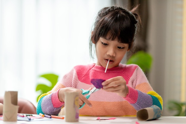 Porträt eines kleinen asiatischen Mädchens, das bei Aktivitäten im DIY-Unterricht an der Schule ein Papier schneidetSchere schneidet Papier