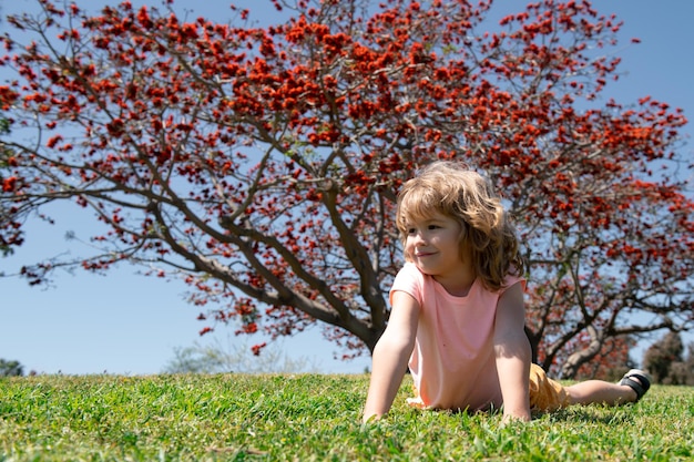 Porträt eines kleinen blonden Jungen, der draußen im Sommerpark spielt. Lustiges Kindergesicht.