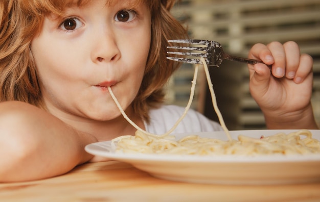 Porträt eines kleinen blonden Jungen, der Pasta Spaghetti isst