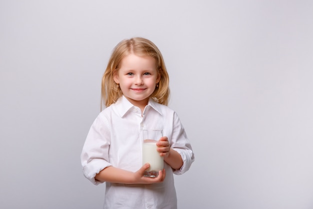 Porträt eines kleinen glücklichen Mädchens mit Gläsern und einem Glas Milch.