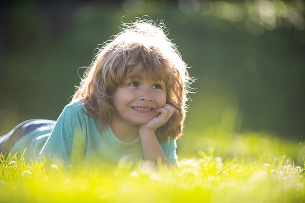 Porträt eines kleinen Jungen, der im Sommernaturpark auf Gras liegt