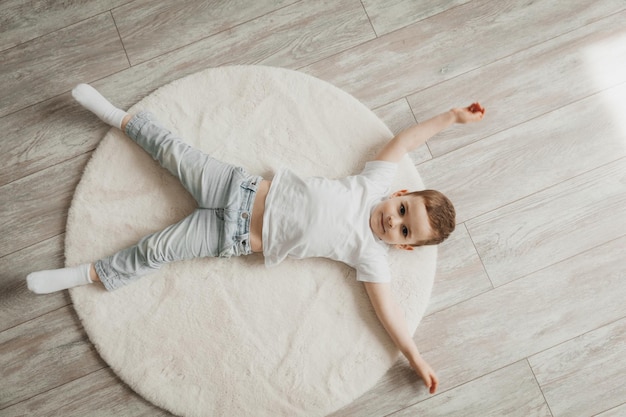 Porträt eines kleinen Jungen, der zu Hause auf einer Teppichbodenheizung liegt