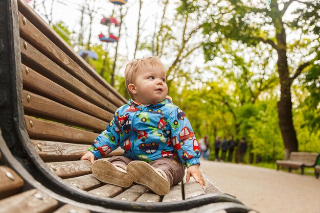 Porträt eines kleinen Jungen im Park auf einer Bank, die Seifenblasen fängt