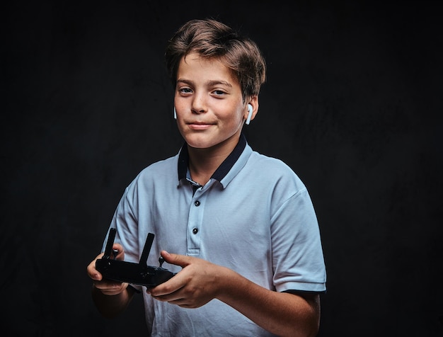 Porträt eines kleinen Jungen in einem weißen T-Shirt, der ein drahtloses Headset trägt und eine Fernbedienung hält.