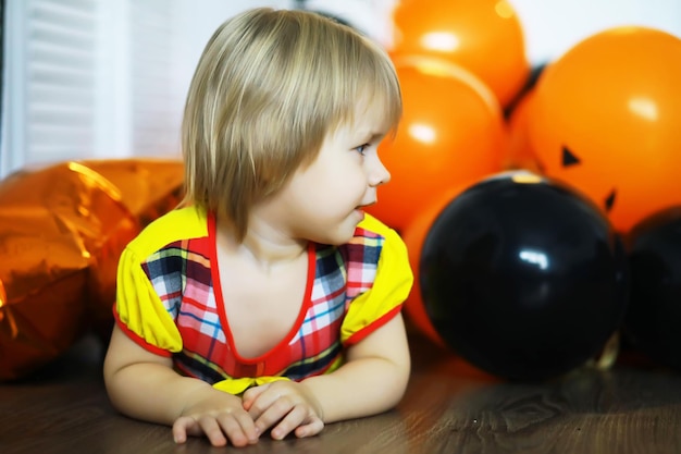 Porträt eines kleinen Kindes, das in einem mit Luftballons geschmückten Raum auf dem Boden liegt. Glückliches Kindheitskonzept.
