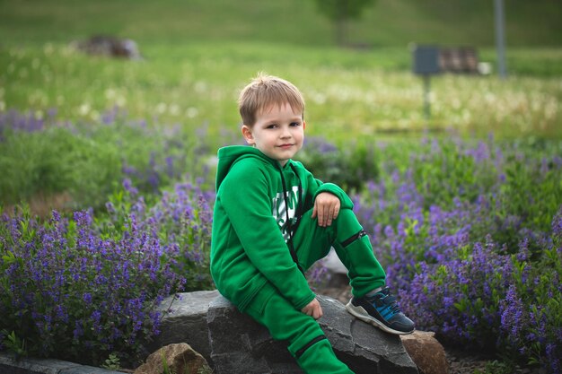 Porträt eines kleinen lächelnden Jungen auf dem Hintergrund eines blühenden Parks