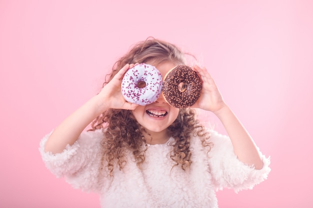 Porträt eines kleinen lächelnden Mädchens mit Donuts