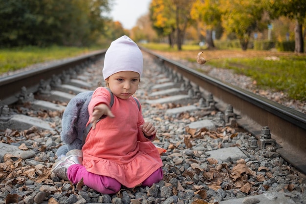 Porträt eines kleinen Mädchens, das auf den Bahngleisen im Wald sitzt