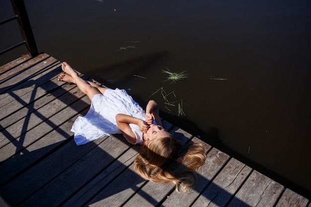 Porträt eines kleinen Mädchens draußen im Sommer am See. Kleines Mädchen im Sommerkleid am Fluss.