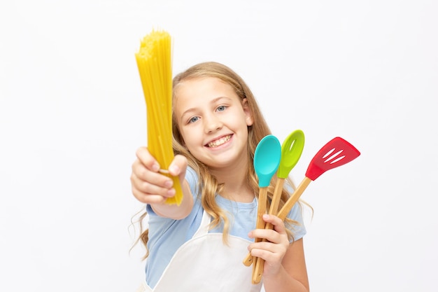 Porträt eines kleinen Mädchens in einer weißen Schürze mit Spaghetti, isoliert auf weißem Hintergrund