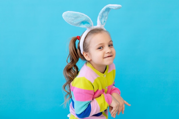 Porträt eines kleinen Mädchens mit Hasenohren in einer gestreiften Jacke Das Konzept der Osterferien Blauer Hintergrund Fotostudio Platz für Text