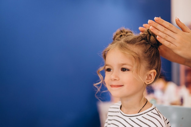Porträt eines kleinen Mädchens mit stilvoller Frisur in einem Schönheitssalon, das die Haare eines Kindes macht