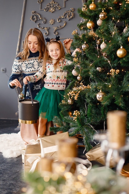 Porträt eines kleinen Mädchens und ihrer Mutter, die Weihnachtsbaum schmücken