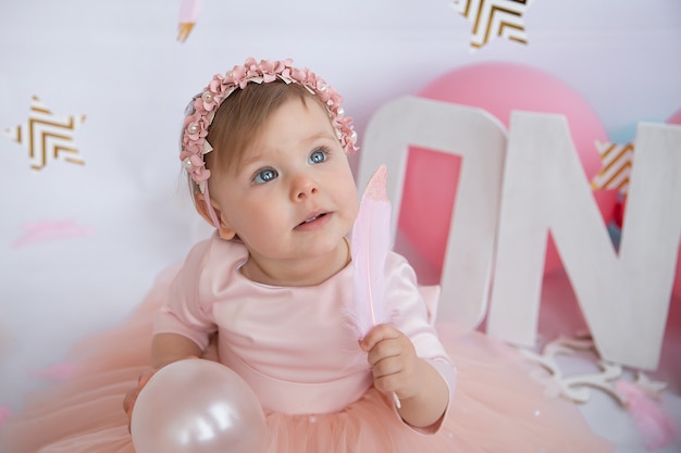 Foto porträt eines kleinen schönen babys. rosa feder in der hand.