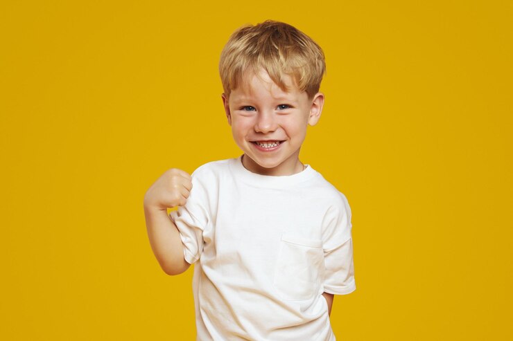 Porträt eines kleinen süßen schüchtern Jungen mit blonden Haaren, der ein weißes T-Shirt trägt und steht und schaut