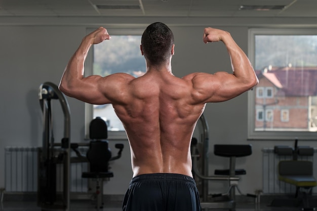 Porträt eines körperlich fitten Mannes, der seinen gut trainierten Körper im Fitnessstudio zeigt
