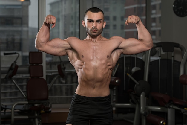 Porträt eines körperlich fitten Mannes, der seinen gut trainierten Körper im Fitnessstudio zeigt