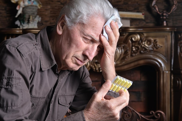 Porträt eines kranken älteren Mannes mit Pillen