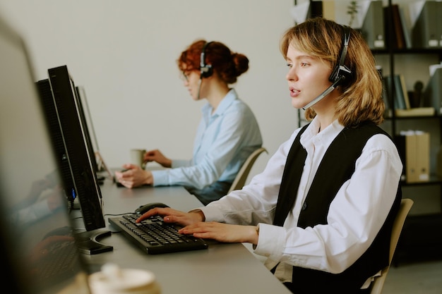 Porträt eines Kundendienstmitarbeiters, der am Schreibtisch im Büro mit einem Headset-Kollegen arbeitet