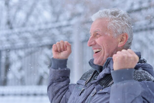 Porträt eines lächelnden älteren Mannes, der im Winter im Freien steht